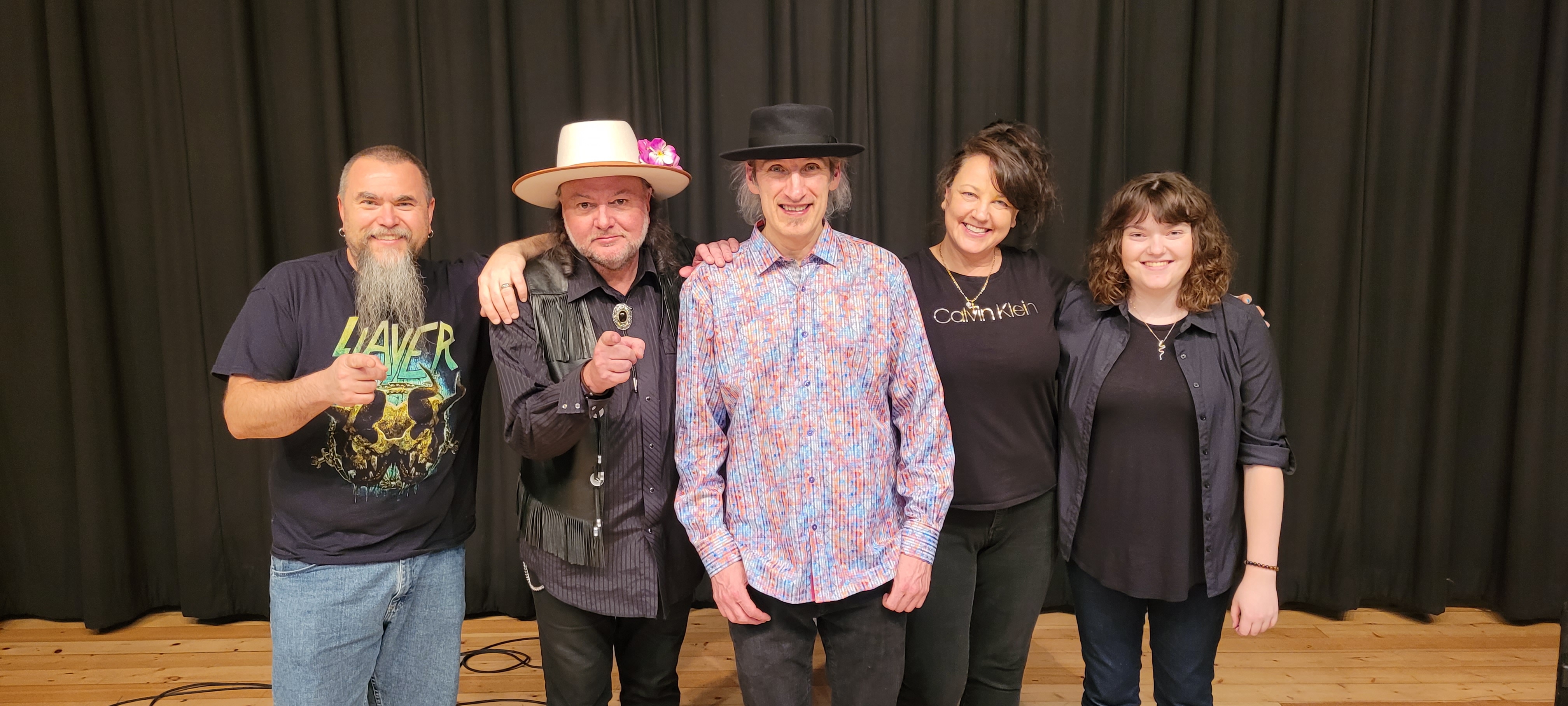 Production team and artists posing together backstage at a theater auditorium stage